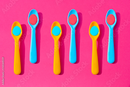 Pattern of yellow and blue plastic teaspoons with blue and red liquid photo