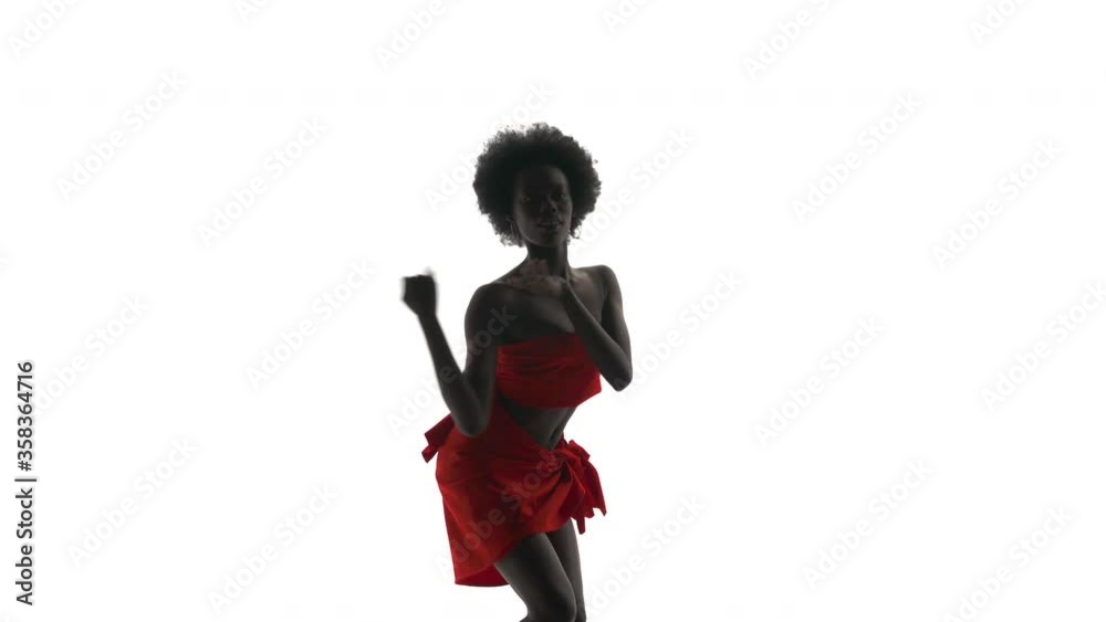 High contrast close-up shot of African woman in red cloth dancing, sensually moving her body and squatting slightly. Isolated, on white background. High contrast close-up shot of African woman in red cloth dancing, sensually moving her body and squatting slightly. Isolated, on white background.