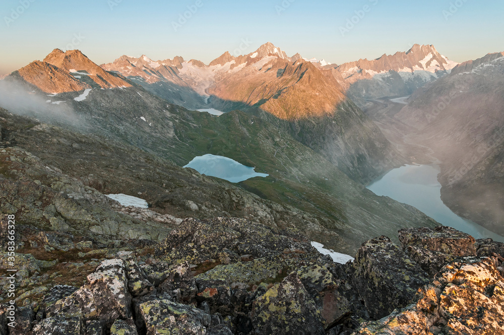 While the Finsteraarhorn and the Lauteraarhorn catch the first rays of the sun, the Unteraar glacier and lake Grimsel below are still shrouded in darkness.