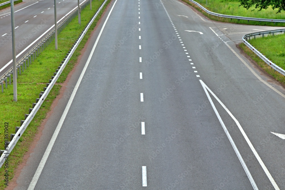 highway with markings and fences without vehicles through the green zone with blurred focus in the background