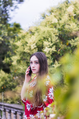 Attractive young woman with red dress making a call outdoor