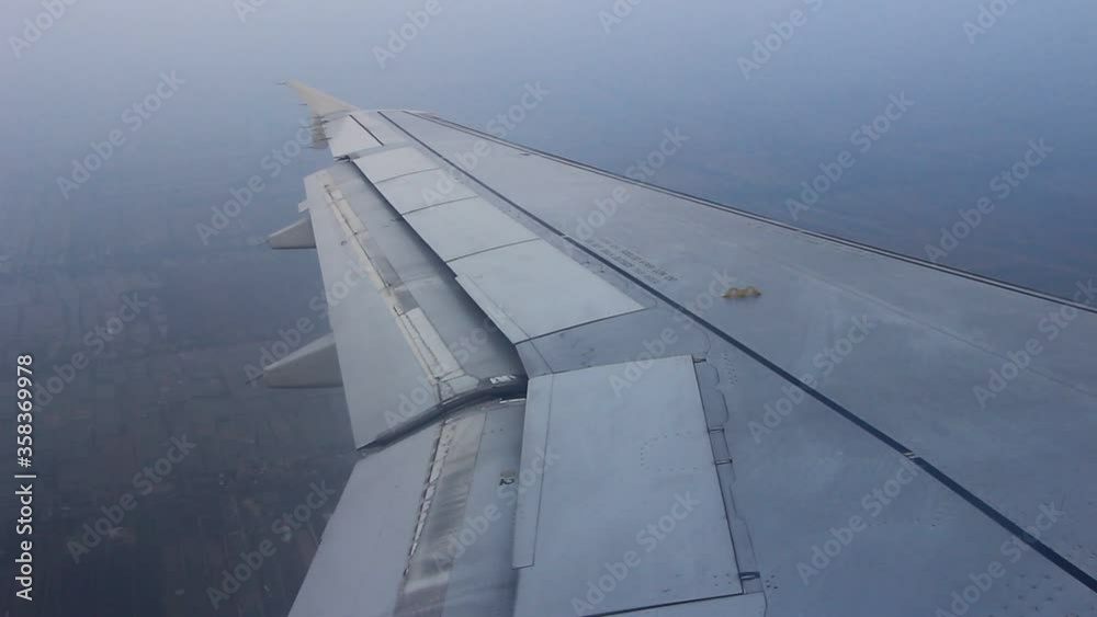 Wing of airplane flying above the clouds in the blue sky Wing of airplane flying above the clouds in the blue sky