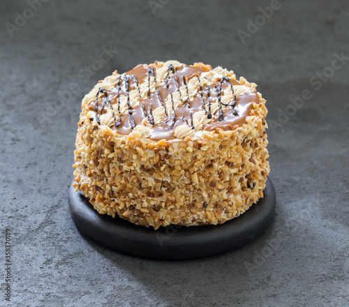 Cake with cream, caramel, nuts and chocolate on a dark background 
