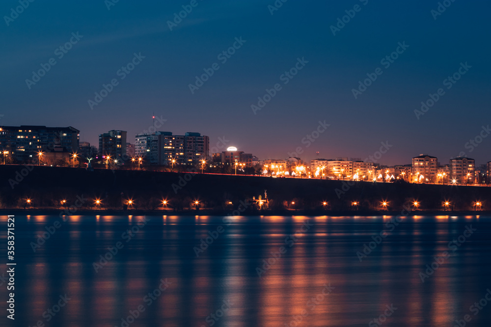 Cityscape of town Galati on Danube river from shore of Braila County, Romania at sunset