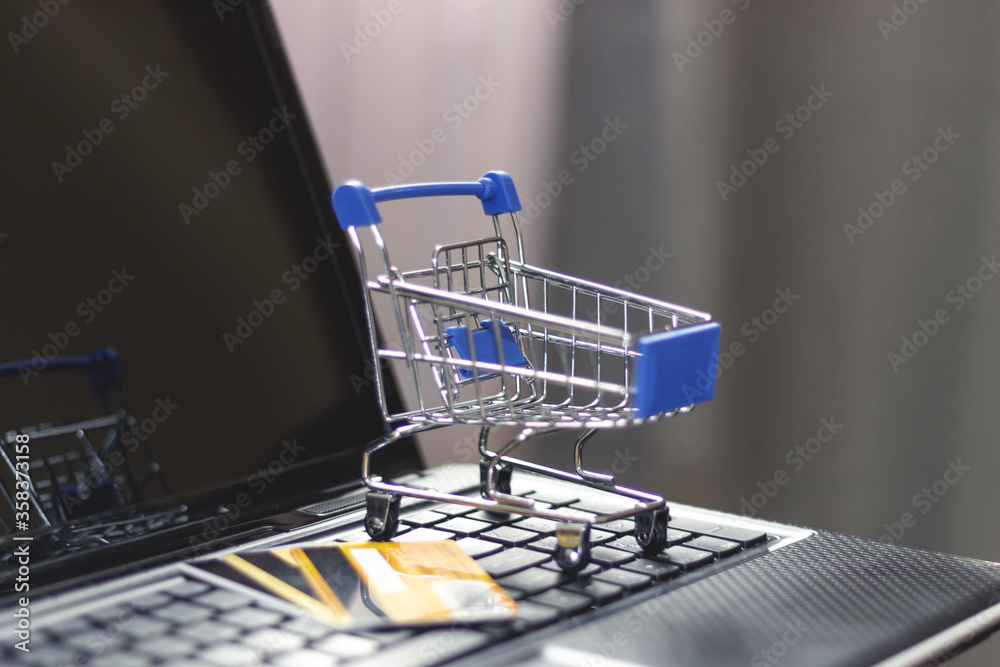 Online shopping with home delivery. Shopping basket on laptop keyboard.
