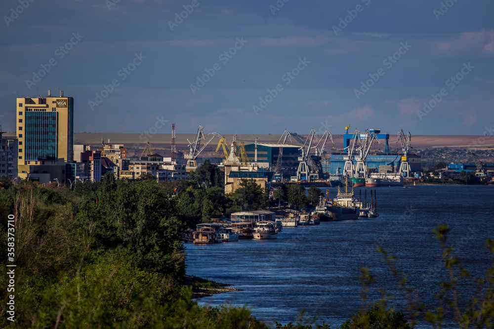 Cityscape of town Galati on Danube river from shore of Braila County, Romania at sunset