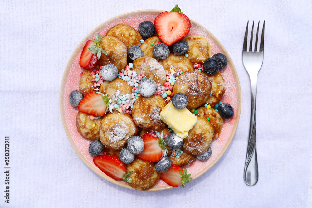 Little pancakes called poffertjes with strawberries, blueberries and colourful candies. Little pancakes called poffertjes with strawberries, blueberries and colourful candies.