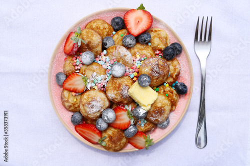 Little pancakes called poffertjes with strawberries, blueberries and colourful candies. 