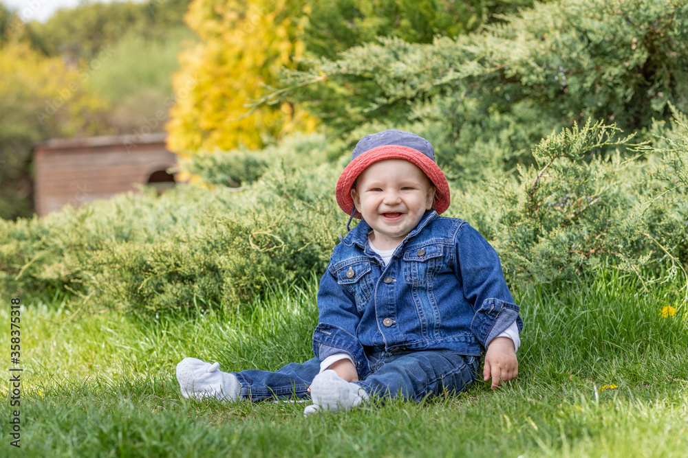 Cute little baby boy sitting outdoors and smiling at the camera Cute little baby boy sitting outdoors and smiling at the camera