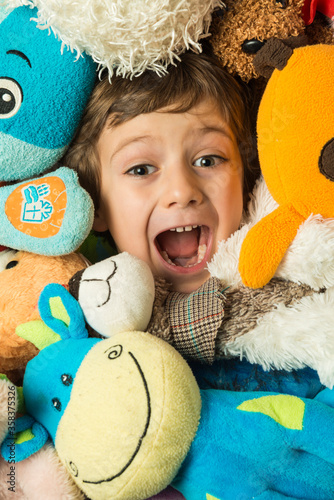 Portrait of a boy with his face surrounded by stuffed animals.