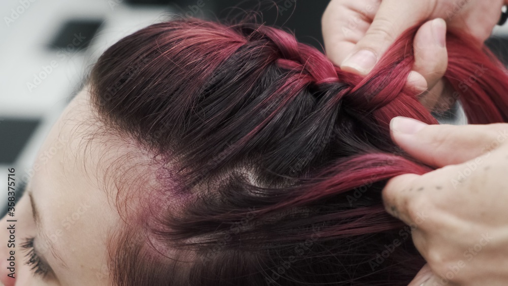 Professional hairdresser plaiting braids to red colored female hair Professional hairdresser plaiting braids to red colored female hair