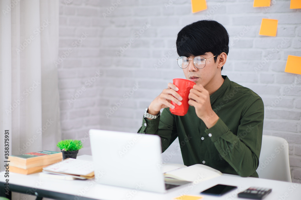 Young businessman working at home and drinking coffee. He look at laptop. Soft and smooth focus and tone Young businessman working at home and drinking coffee. He look at laptop. Soft and smooth focus and tone