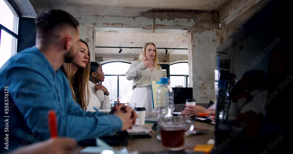 Successful young blonde female business coach giving speech for employees team at modern loft office slow motion. Successful young blonde female business coach giving speech for employees team at modern loft office slow motion.
