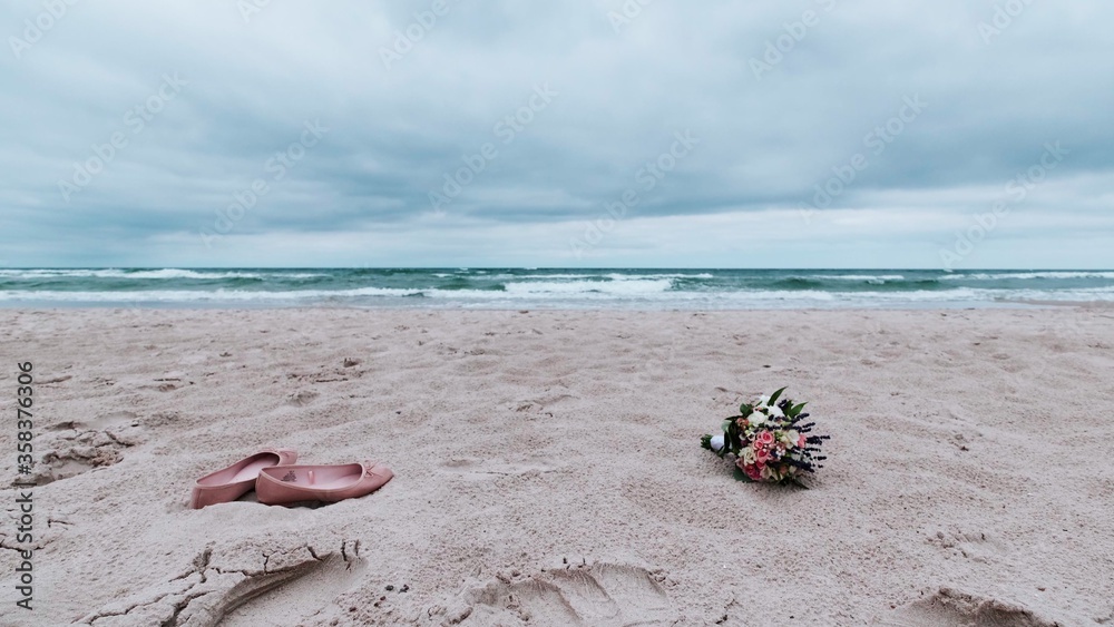 Beautiful bouquet with red and white roses and shoes over sand of beach Beautiful bouquet with red and white roses and shoes over sand of beach