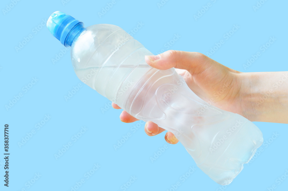 Bottle of water in the hand. Hand holds a bottle of water. Blue background. Bottle of water in the hand. Hand holds a bottle of water. Blue background.