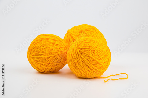 three balls of yellow thread for knitting or crocheting on a light background