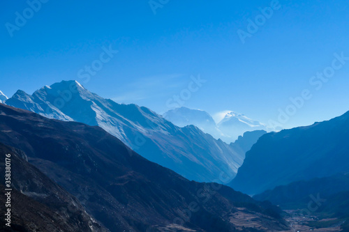 View on high Himalayas along Annapurna Circuit Trek, Nepal. Harsh and barren landscape around. Clear and blue sky. High Himalayan ranges around. Snow capped mountains. Serenity and calmness