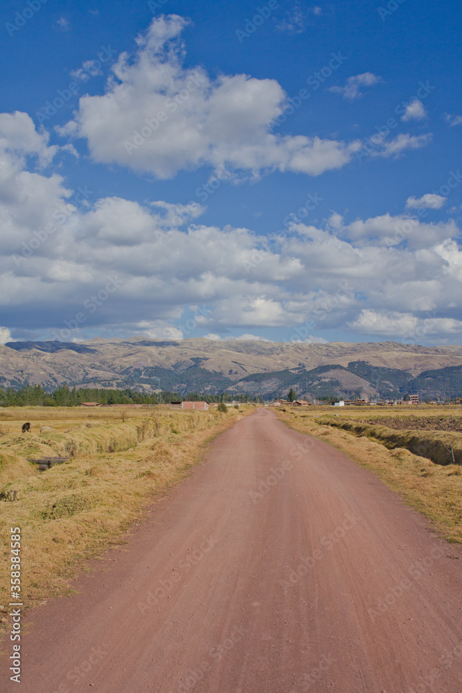 dirt road with mountains and blue sky