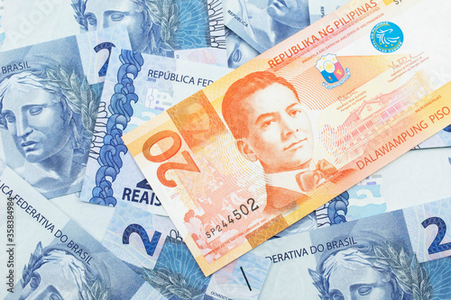 An orange twenty piso bank note from the Philippines with Brazilian two reais bank notes close up in macro