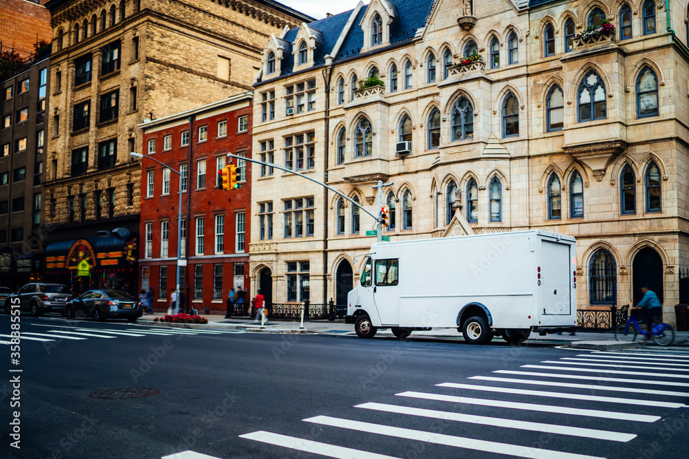Freight van for transportation goods for delivery service moving on avenue in downtown, white truck automobile body with copy space area for advertising content or commercial information on street