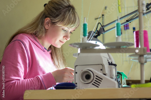 Girl happily sews on a professional sewing machine