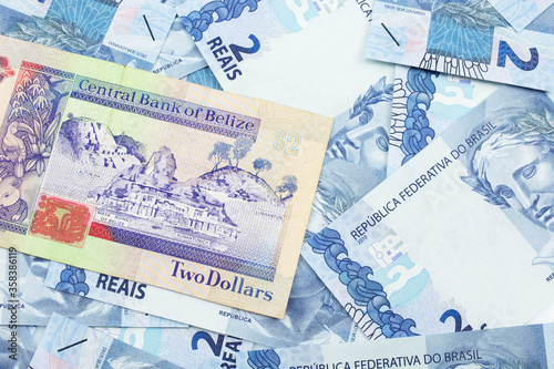 A close up image of a colorful two dollar bill from Belize with a pile of Brazilian two reais bank notes in macro