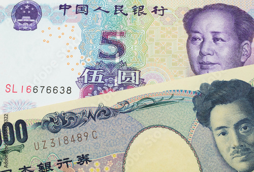 A macro image of a Japanese thousand yen note paired up with a purple, blue and white five yuan bank note from China. Shot close up in macro.
