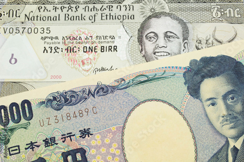 A macro image of a Japanese thousand yen note paired up with a grey Ethiopian one birr bill. Shot close up in macro.