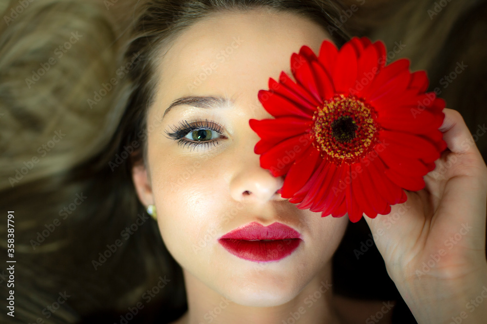 Portrait of a girl with a red gerbera flower.