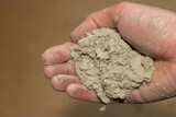 A hand holds a large piece of dust in a dusty and dirty house.
