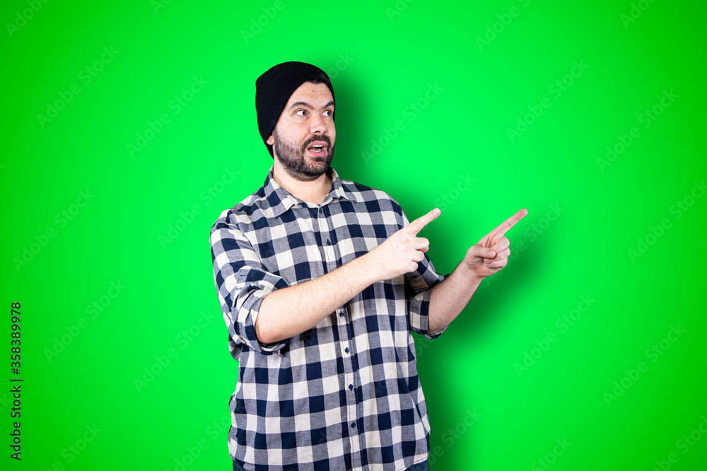 Young man pointing and looking at copy space. Handsome young businessman isolated on green background Young man pointing and looking at copy space. Handsome young businessman isolated on green background