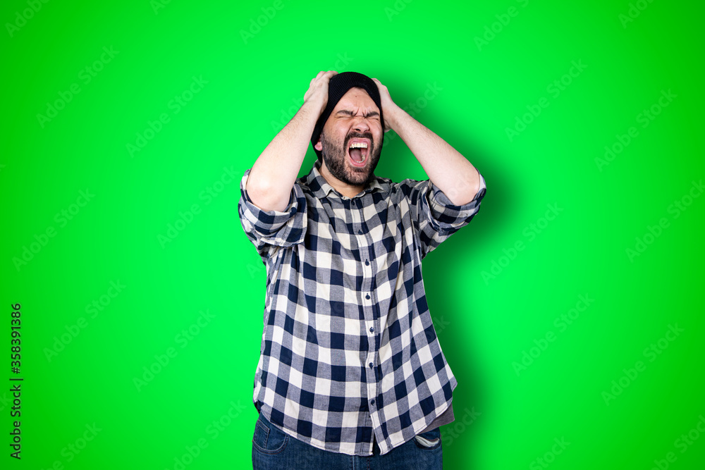 Portrait of a puzzled bearded man holding hands on his head isolated over chroma background Portrait of a puzzled bearded man holding hands on his head isolated over chroma background