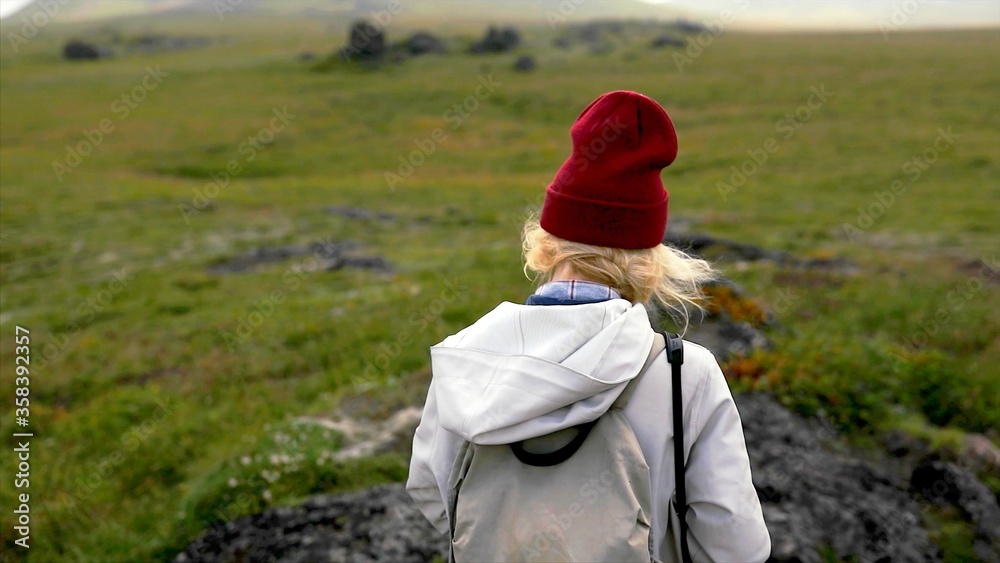 Back of a blond woman who is walking in the nature