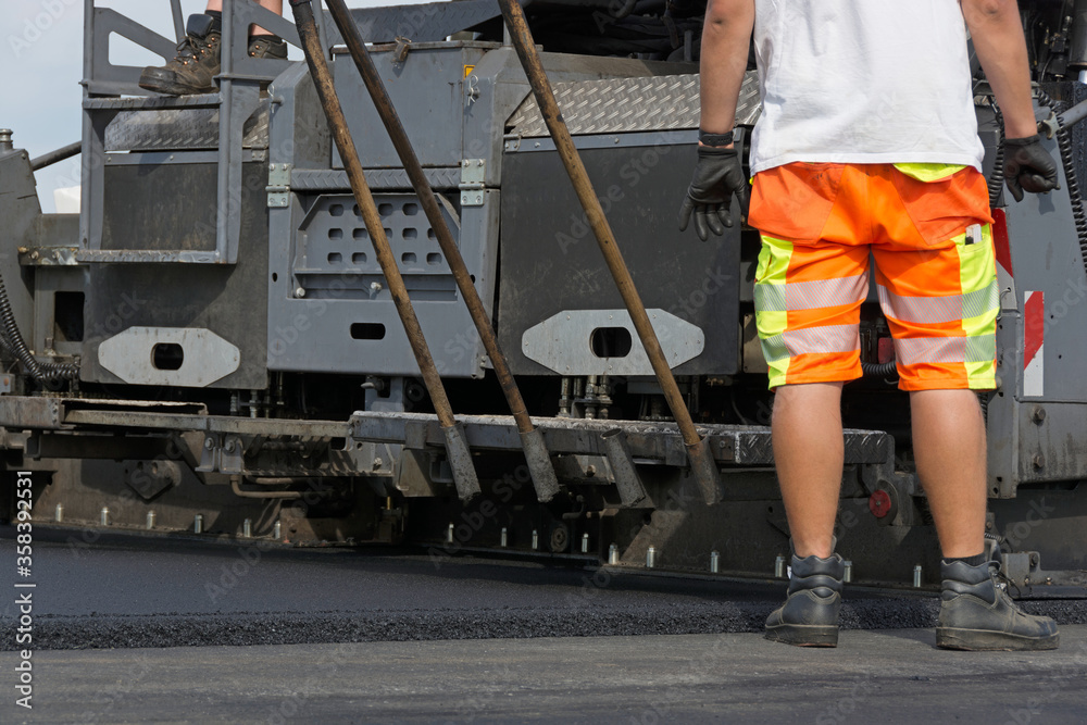 Fototapeta premium Schwarzdeckenfertiger baut Asphalt ein