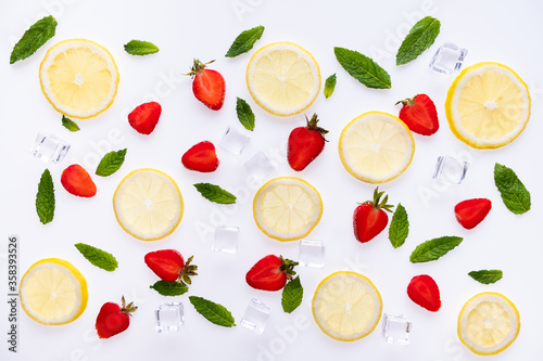 Fototapeta Naklejka Na Ścianę i Meble -  Lemonade ingredients concept pattern on white background. Lemon slices, mint leaves strawberry, and ice cubes.
