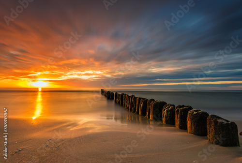 beautiful sunset on the Baltic Sea  waves washing the old wooden breakwaters