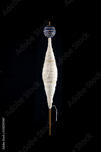 фотографія ancient hand spindle used for spinning coton and making yard on black background