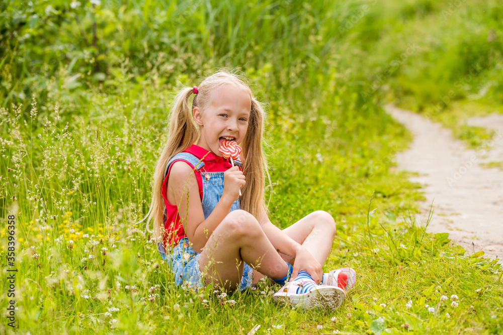 Blonde little girl with long hair and candy on a stick Blonde little girl with long hair and candy on a stick