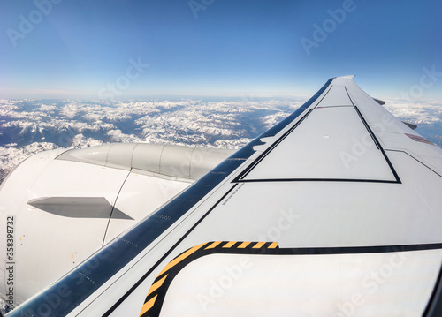Clouds  mountains and sky seen through window of an aeroplane. Wing and engine of a modern fuel efficient twin-jet aircraft 