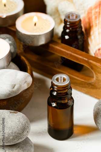 Spa composition with essential oil  stones  shell  soft towel  candle. Aromatherapy and relax  atmosphere of serenity and relaxation. Close up  macro view. White wooden background  tonned