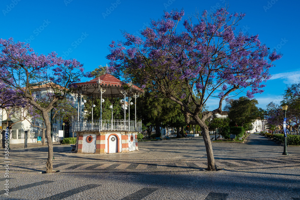 Palco de música en Plaza Don Francisco Gómez  Praça Dom Francisco Gomes en Faro Portugal en un día de sol con jacaranda en flor y cielo azul