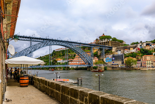 Outdoor restaurant terrace by Dom Luis I bridge in Ribeira and the Douro river with tourist boats in Porto, Portugal © SvetlanaSF