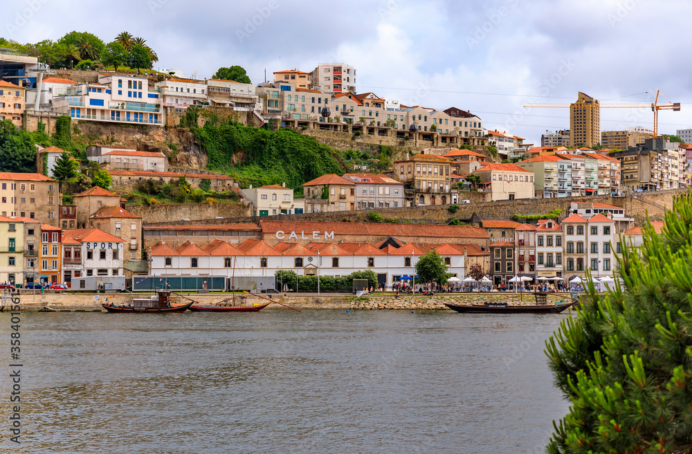 Rabelo boats with barrels of port docked on the Douro in front of the famous Portuguese wine cellars in Porto, Portugal