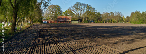 Panorama picture of a freshly tilled field on a sunny spring day in the district Wesermarsch (Germany), a traditional farmhouse can be seen in background