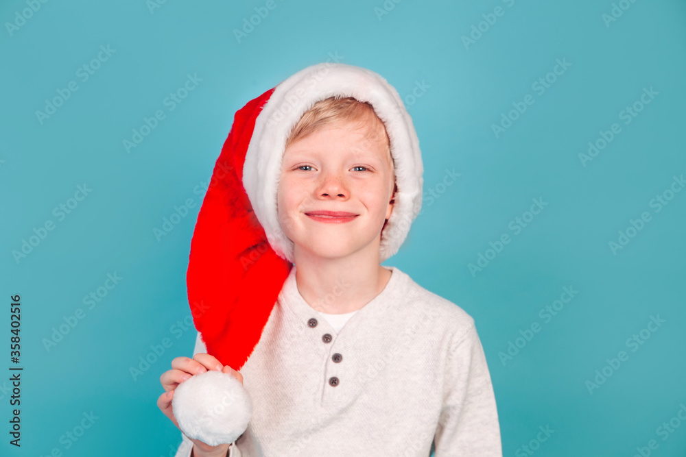 Smiling funny child in Santa red hat on blue backround. Christmas concept. Smiling funny child in Santa red hat on blue backround. Christmas concept.