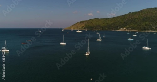 yachts, catamarans, motor boats in the bay, calm sea, part of the coast is visible, cape, hill
