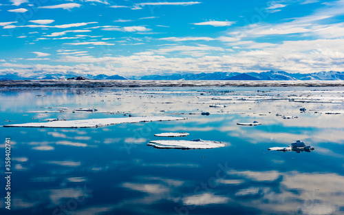 Blue sky and Ice pieces on the water in Arctic