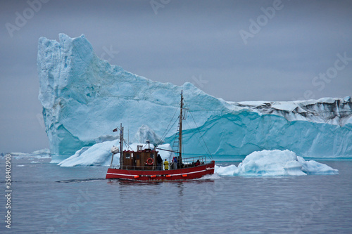 Converted fishing boat among enormous icebergs in Disko Bay, Illulissat, Greenland © Michele Burgess