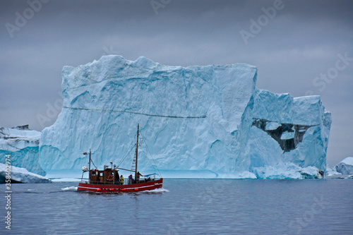 Converted fishing boat among enormous icebergs in Disko Bay, Illulissat, Greenland