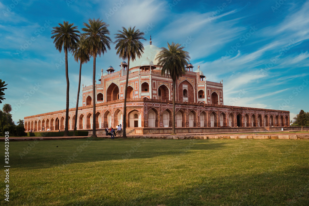 Humayun tomb behind palm tree and dramatic blue sky in the background